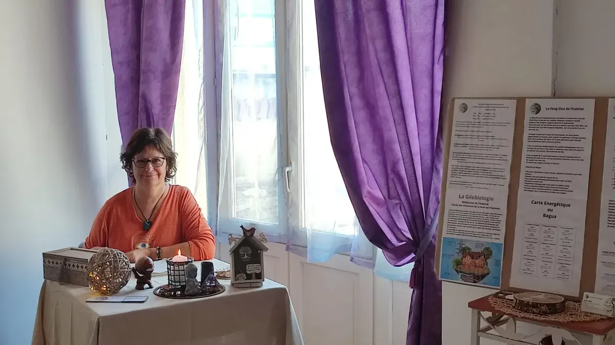 Sylvie Tauzin dans son espace de consultation, devant ses panneaux sur la géobiologie et le feng shui